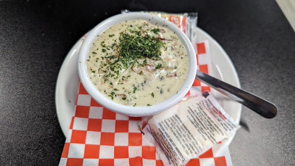 A bowl of Pacific Northwest clam chowder, thick and creamy, finished with fresh herbs and served with crackers.