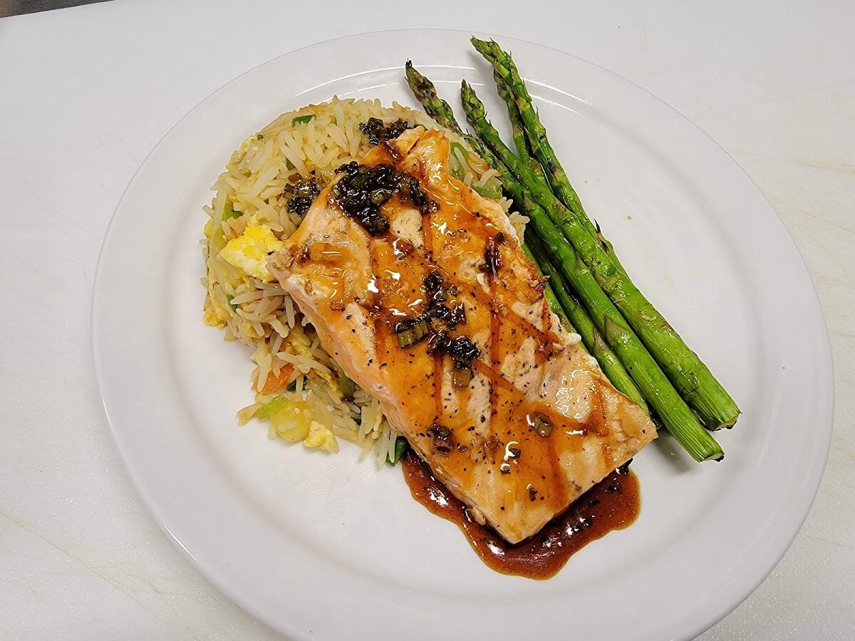 Grilled salmon fillet glazed and served over vegetable fried rice with grilled asparagus.